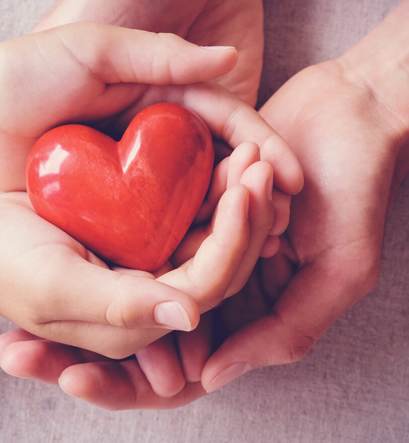 Four hands holding a ceramic heart
